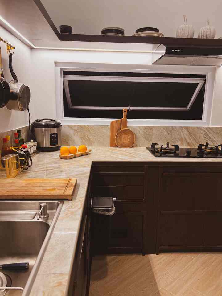 Modern kitchen featuring natural wood tones and beige marble countertops with a compact layout