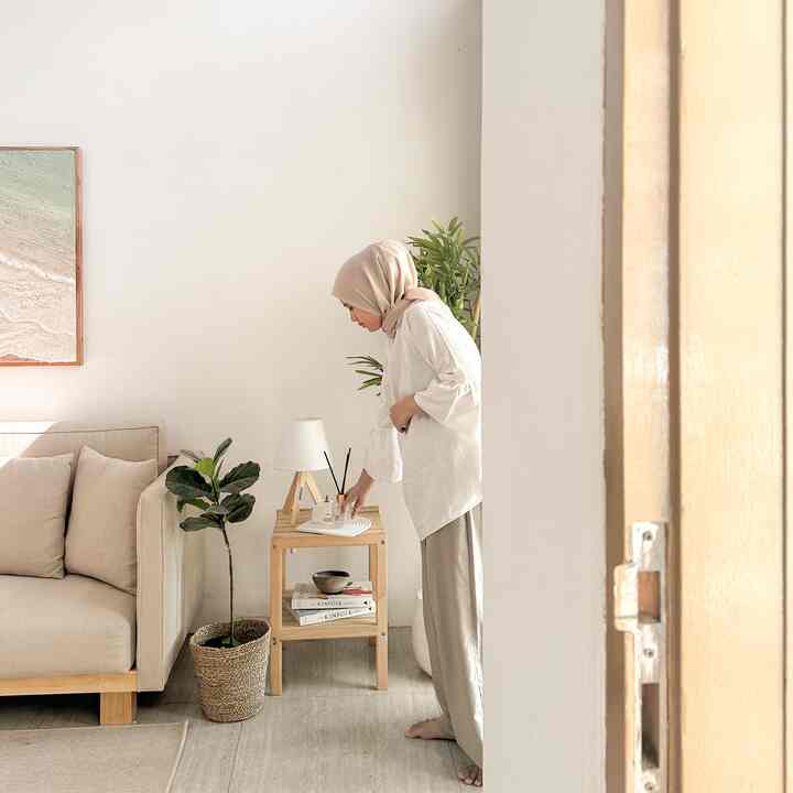 Beige and brown toned living room featuring sofa, wooden shelf, and plants with a natural and cozy atmosphere