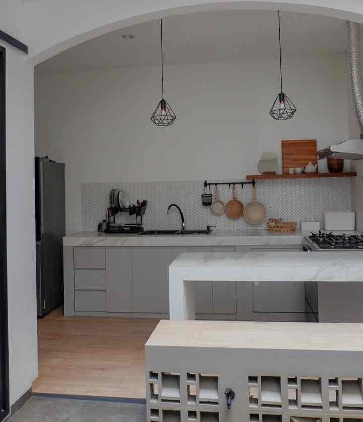 Modern kitchen in white and gray tones featuring marble countertops and pendant lights in a compact semi-outdoor space