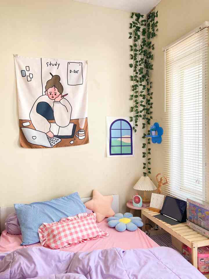 Light brown-walled cozy bedroom featuring pink bedding, playful wall decor, and a window with blinds on the side