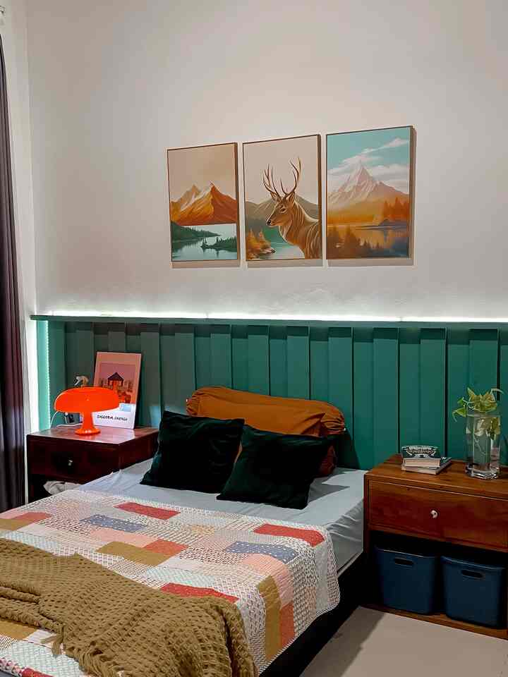 Emerald green toned bedroom featuring a green headboard and an orange table lamp creating a cozy Bohemian atmosphere