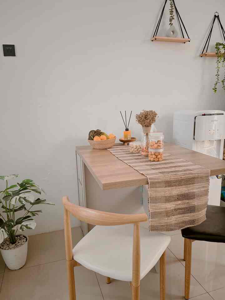 White-walled dining room with wood tone dining table, featuring minimalistic and natural home cafe ambiance