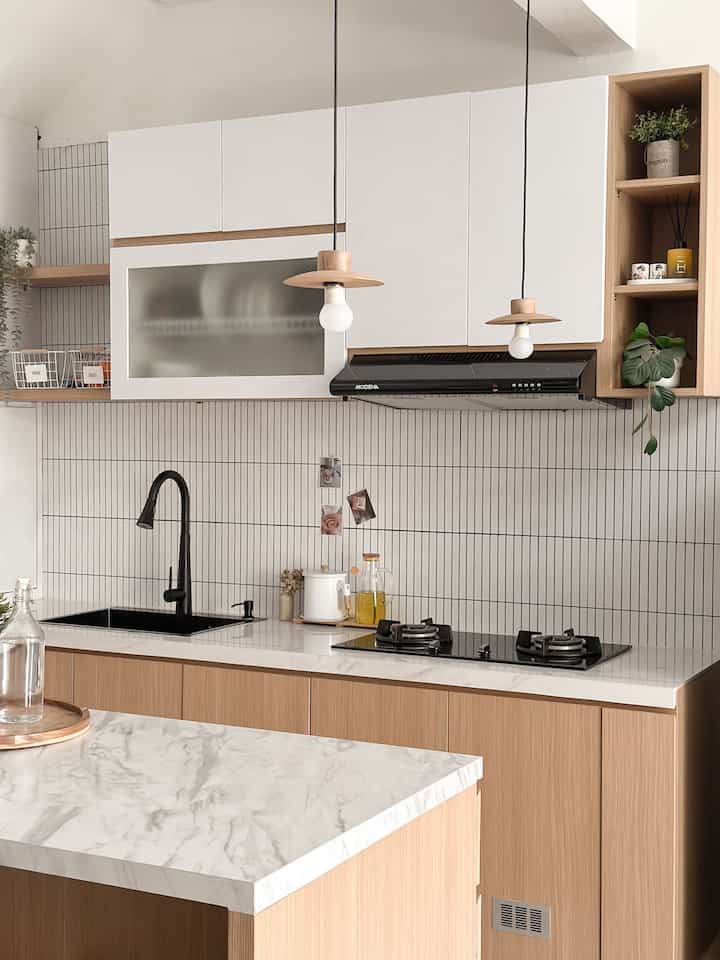 A modern kitchen with a harmonious white and wood tone, featuring a marble kitchen island and pendant lights in a clean setting