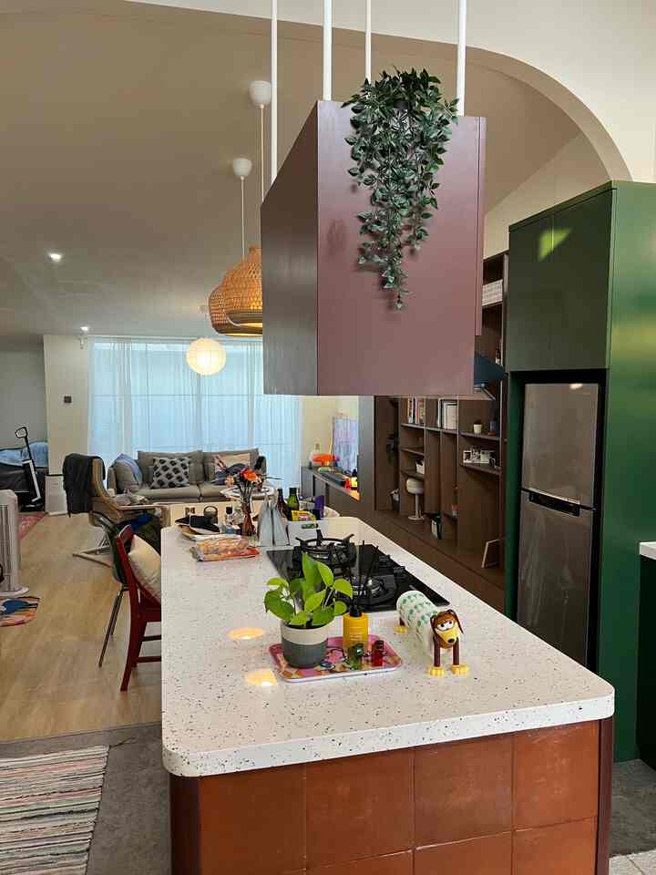 Natural and green toned kitchen and living room featuring a large kitchen island and sofa in a modern open space