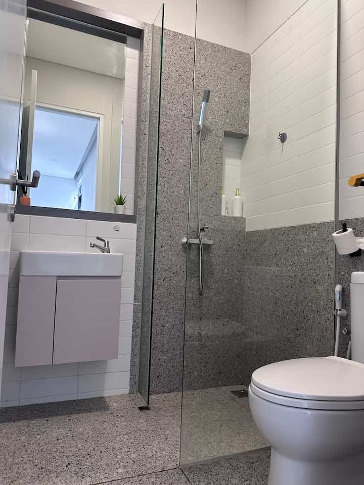 White and gray toned bathroom featuring sink and transparent glass shower area with clean modern design