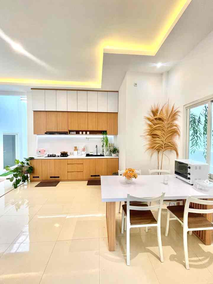 White and wood tone kitchen and dining room featuring minimalist design that creates a spacious and modern atmosphere