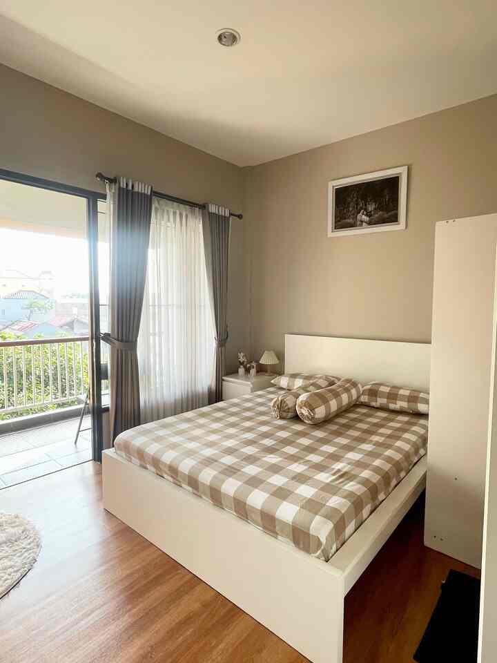 Beige and white toned bedroom featuring a large window and balcony, creating a bright and natural atmosphere