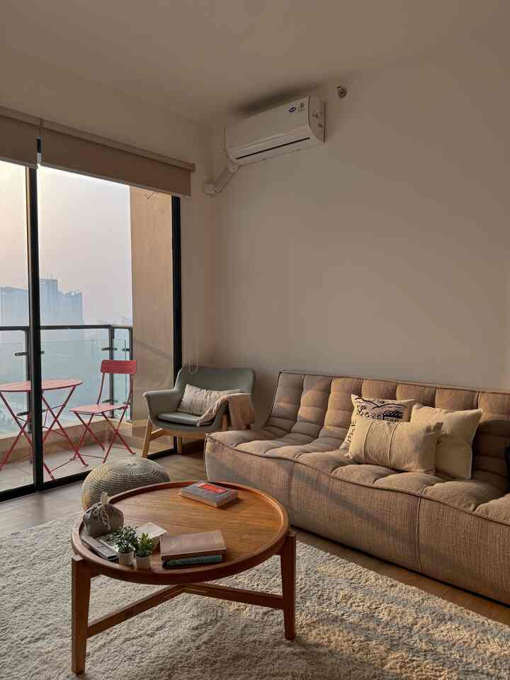 Beige-toned living room featuring a beige sofa and wooden coffee table with a cozy atmosphere and visible balcony