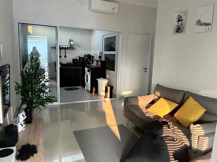 White and gray toned living room featuring a gray sofa with yellow cushions and sliding doors revealing a kitchen