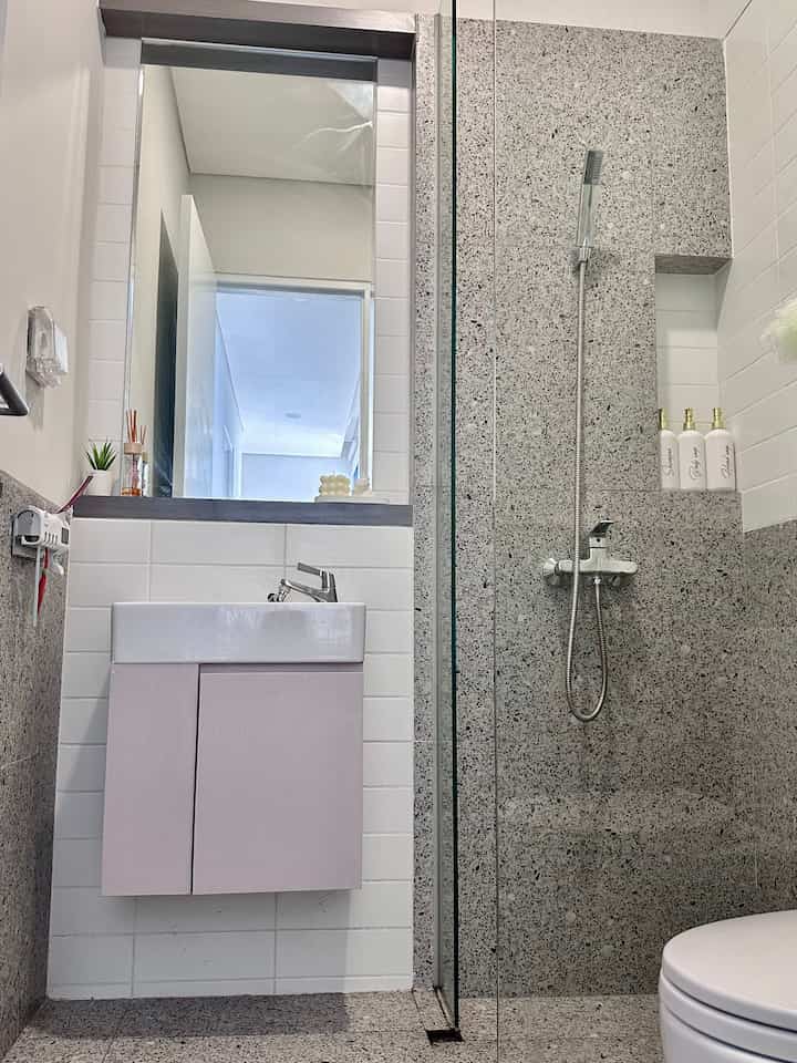 White and gray toned bathroom featuring a sink and shower area with a clean, modern design