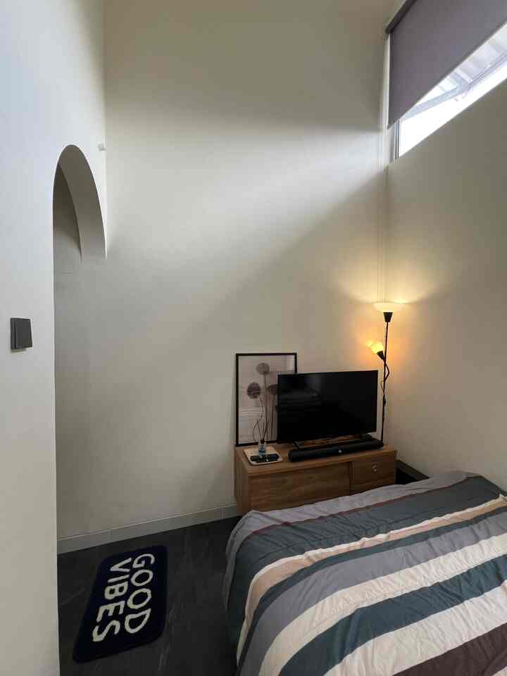 Small bedroom with white walls, black floor lamp, wooden nightstand, and striped bedspread