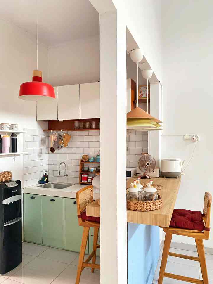 Compact kitchen with white walls and wood-tone bar stools, featuring a red pendant light as a focal element