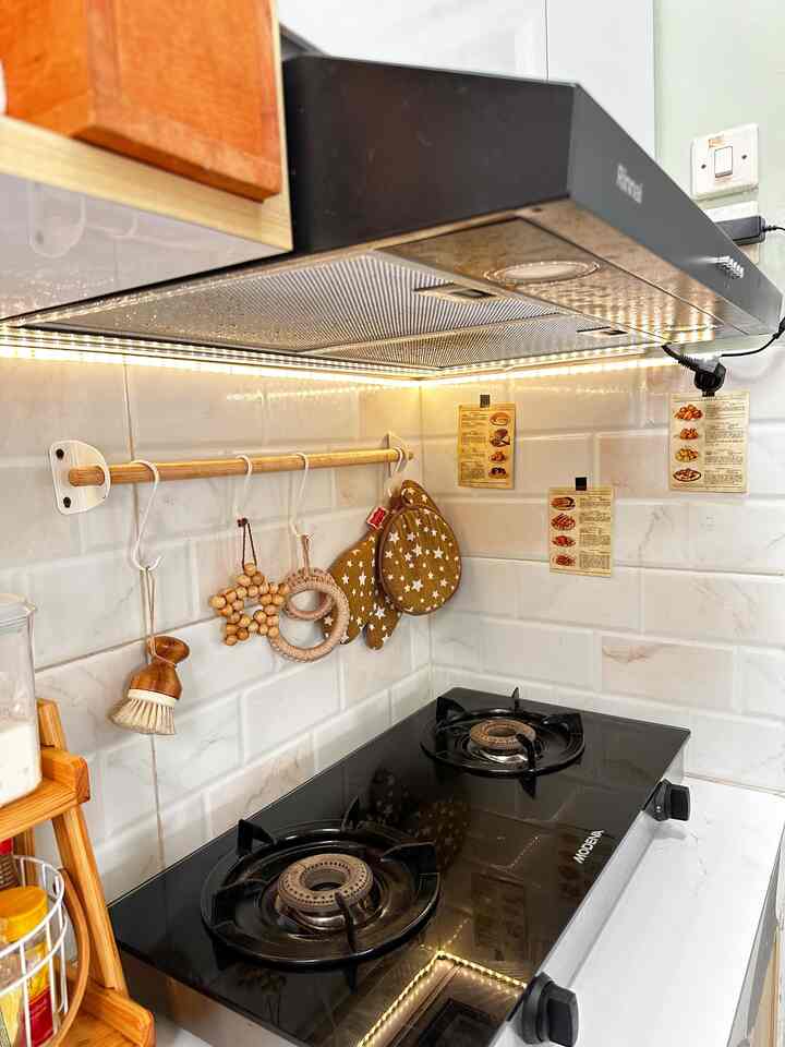 Black and wood tone kitchen featuring a gas range and neatly arranged kitchen utensils in a cozy setting