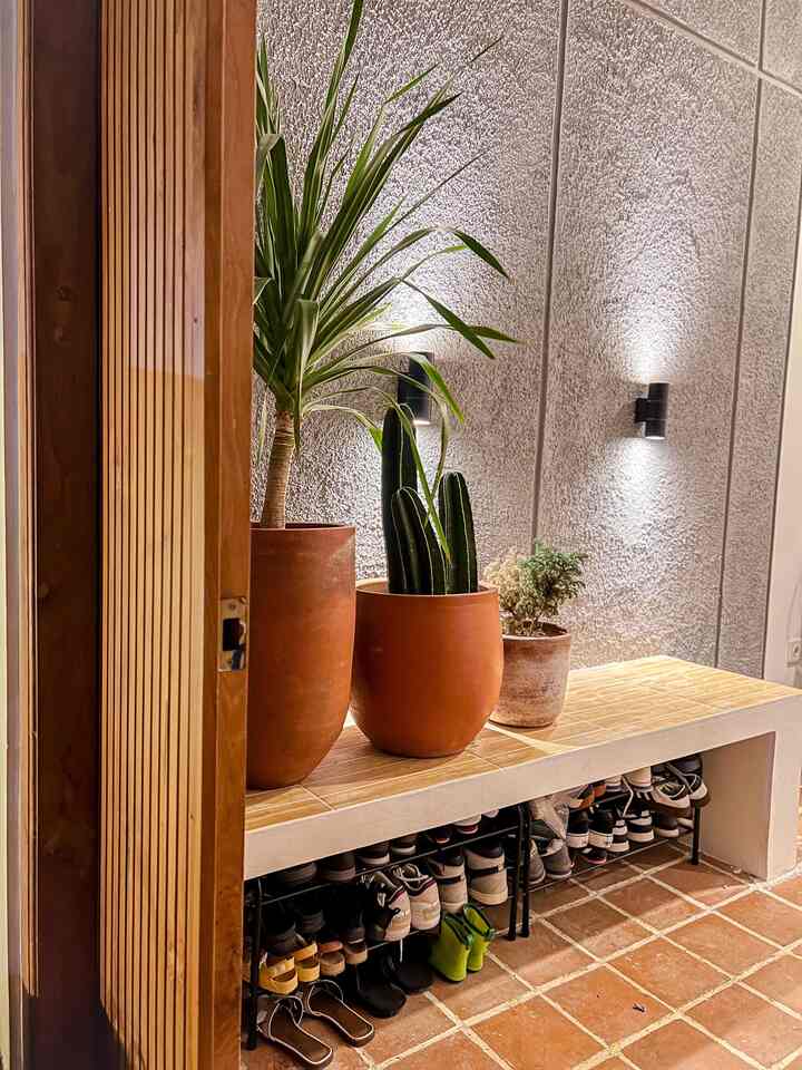 Entrance space with beige tiled floor and wooden tone bench featuring terracotta pots and cactus plants