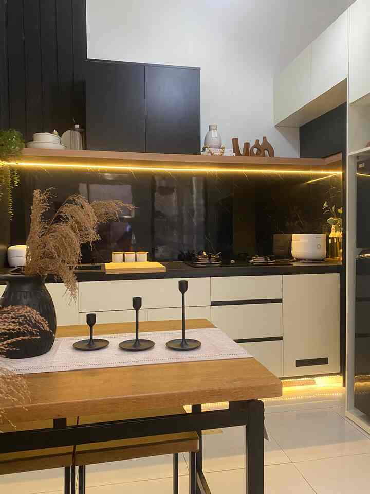 Modern kitchen space featuring natural light brown wood dining table with black and white cabinetry illuminated by warm lighting