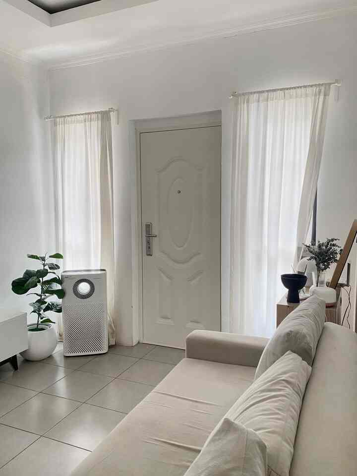 White and beige dominated living room featuring a beige sofa and green plant creating a cozy atmosphere