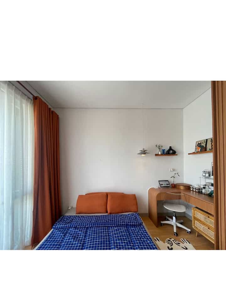 Modern bedroom with brown curtains and navy bedding, featuring a desk and chair creating a cozy space