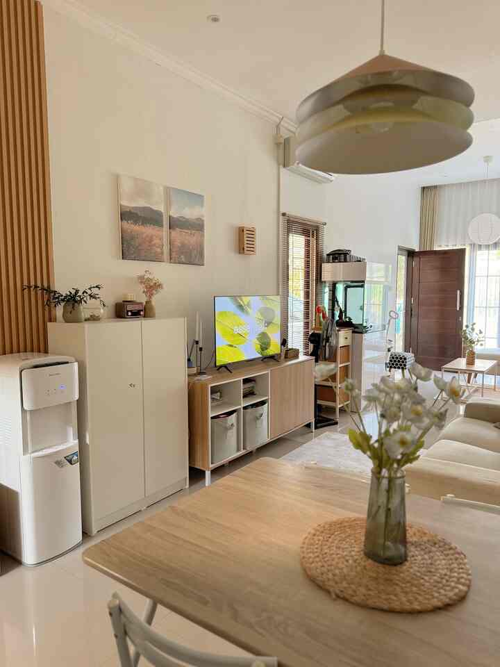 White-walled living room with wood tone furniture, featuring a beige sofa and TV stand creating a natural atmosphere