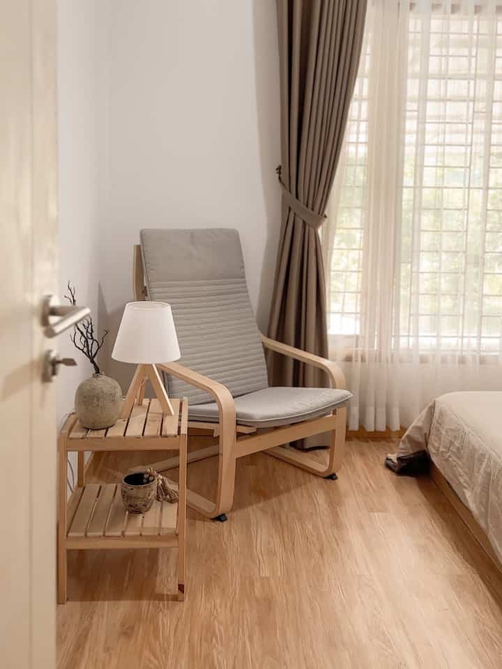 Natural tones and wood flooring bedroom featuring an armchair and curtains with a cozy atmosphere