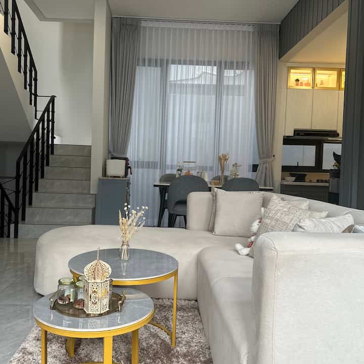 Bright beige and gray toned living and dining room featuring modern sofa and coffee tables with a natural atmosphere