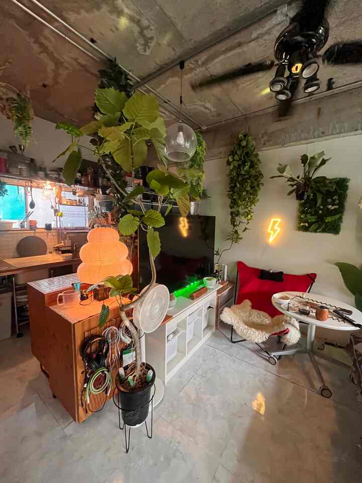 白い床とインダストリアルな天井が印象的なワンルームのリビング、赤いリクライニングチェアと観葉植物が配置されたモダンな空間