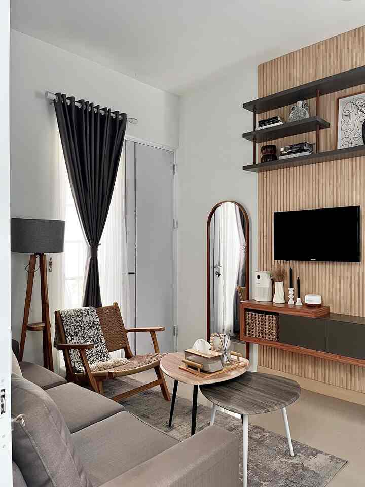 A cozy small modern living room with gray and wood tones, featuring a sofa, lounge chair, and coffee tables