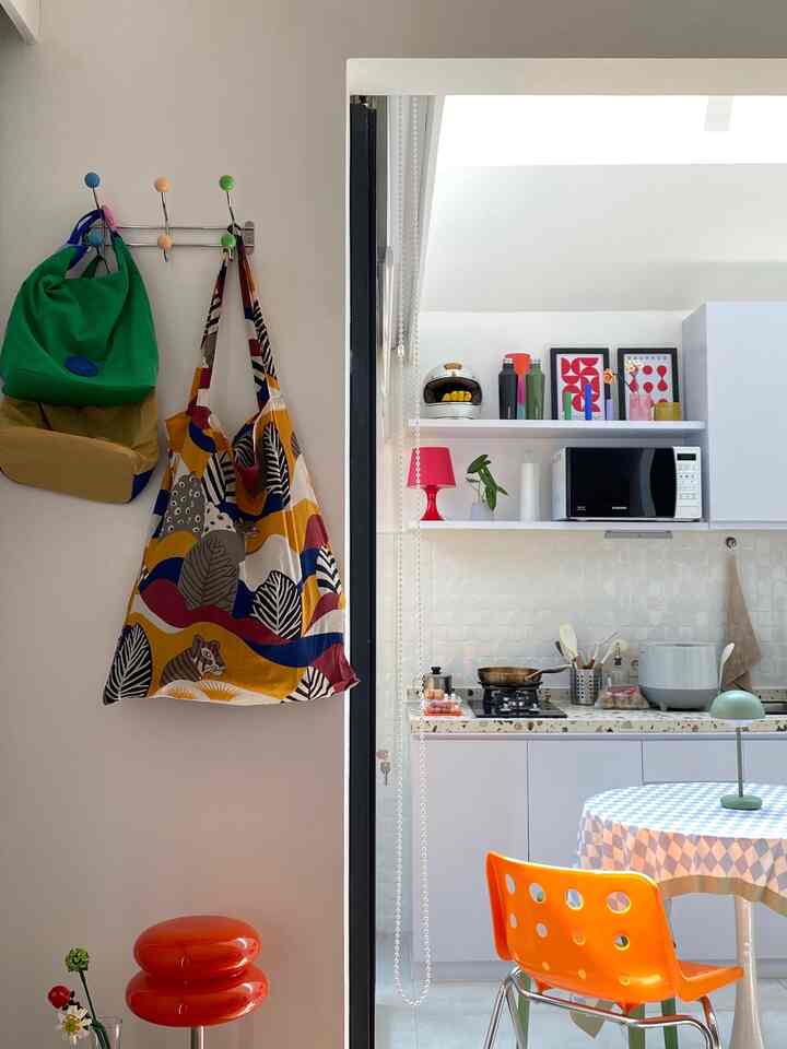 Bright and cozy kitchen space with white walls, an orange dining chair, and blue checkered tablecloth on dining table