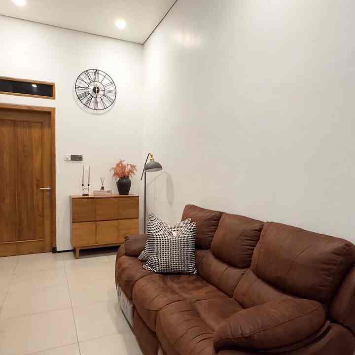 Modern and simple living room with white walls, brown sofa, and wooden cabinet