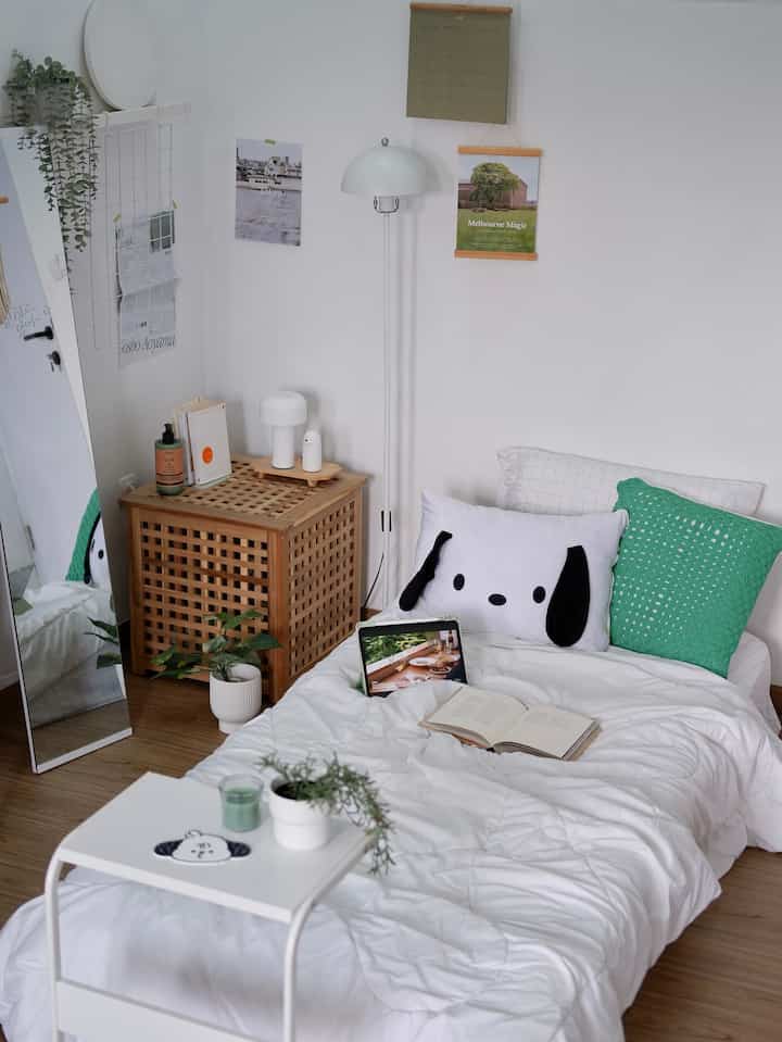 A white and natural brown toned bedroom featuring clean bedding and cushions with a cozy personal atmosphere