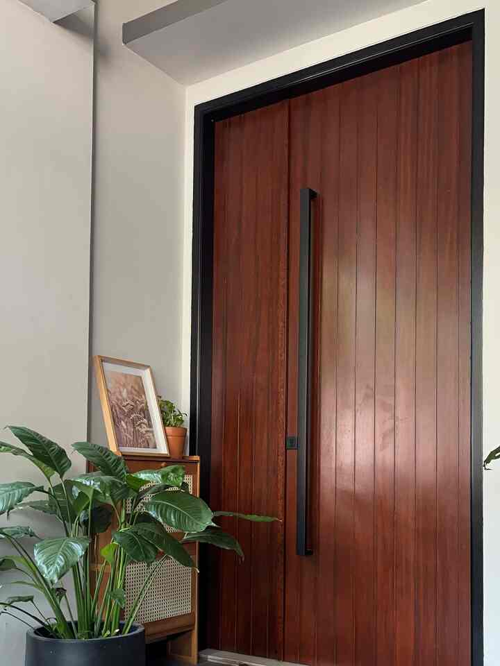 Natural toned entrance featuring large wood tone door with plants creating a cozy atmosphere