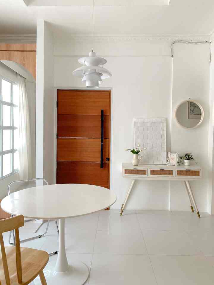 Modern entrance space with white and brown tones featuring a round dining table and console table in a clean interior