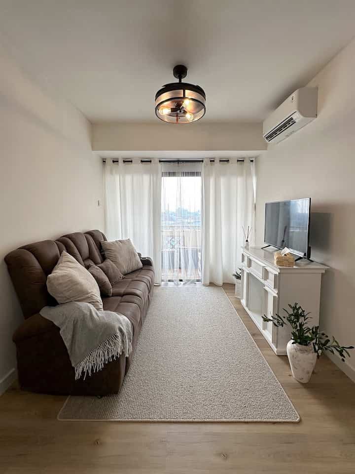 Natural tone living room featuring brown sofa, white curtains, and custom fireplace