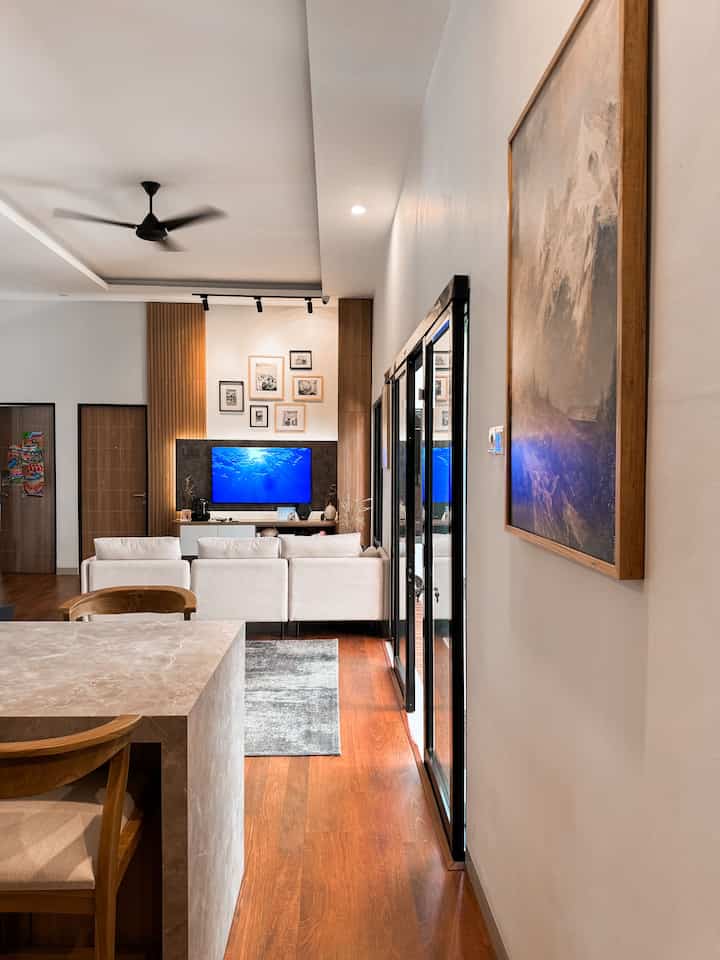 Modern living room with brown wood tones and white furniture, featuring a TV and wall art creating a warm atmosphere