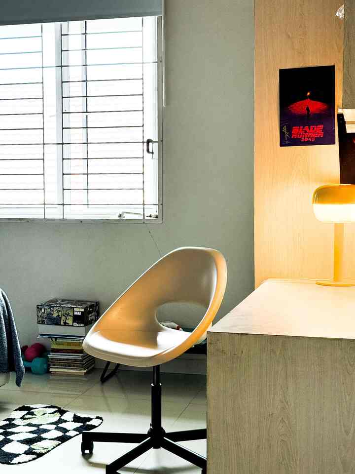 Simple home office space in white and black tones featuring a light wood desk and a white plastic armchair with a clean atmosphere