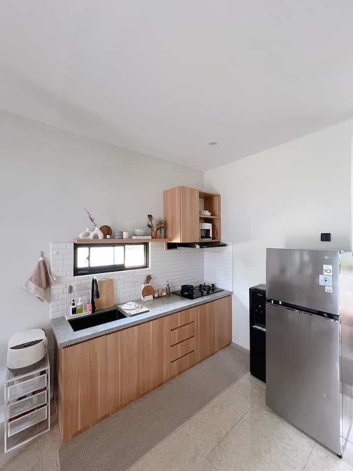 A Scandinavian style kitchen with white walls and wood tone cabinets featuring a sleek granite countertop and modern appliances