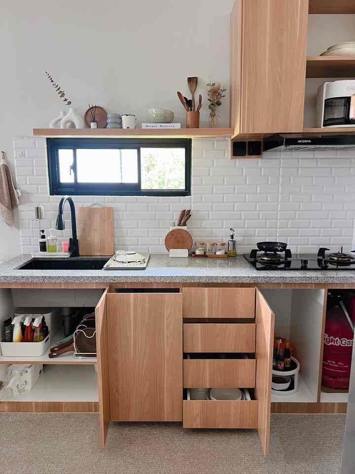 Natural kitchen space featuring white tiled backsplash and wood tone cabinetry with organized storage