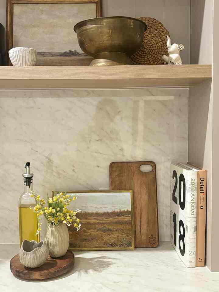 Beige and wood tone kitchen space featuring an oil bottle, cutting board, and framed picture arranged cozily