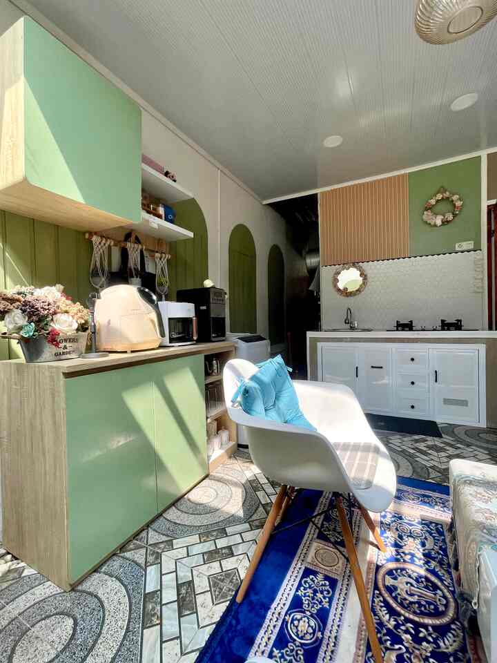 Natural color and modern design blend in a small kitchen space featuring green cabinets, a white chair, and patterned tiled floor creating a cozy atmosphere