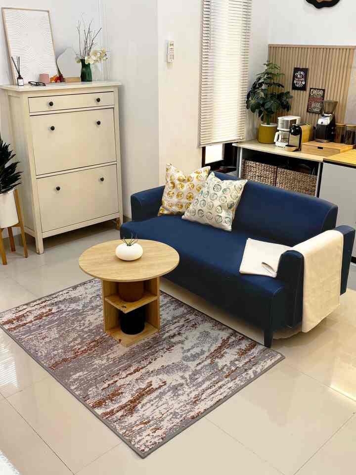 Bright modern living room with a navy sofa and wooden coffee table arranged neatly