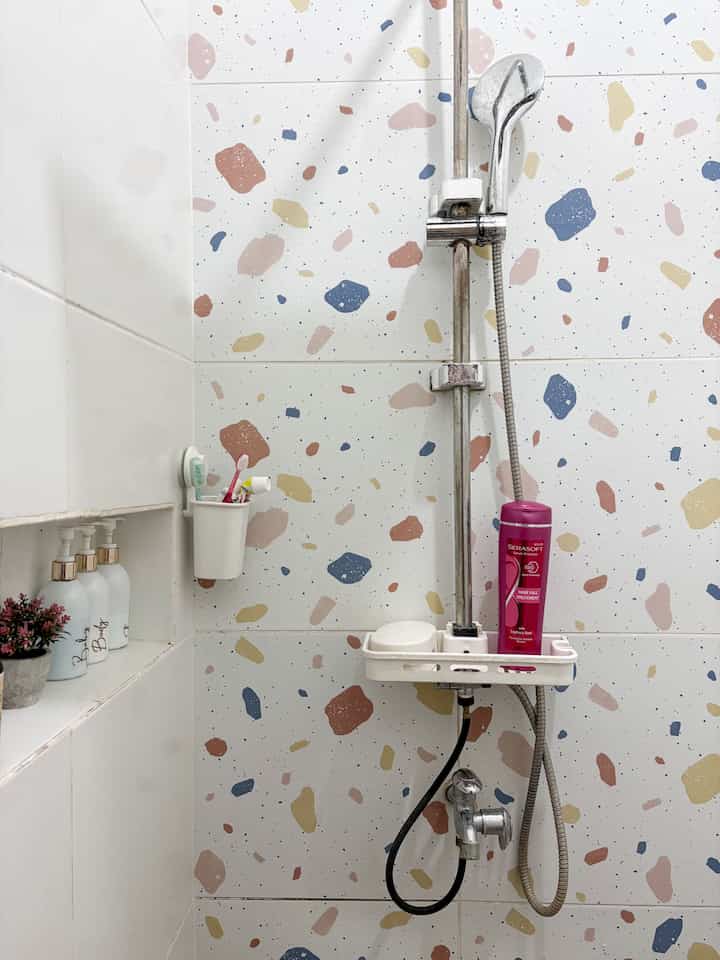 Bathroom shower area with white background and colorful terrazzo tile pattern, exhibiting a clean and compact atmosphere
