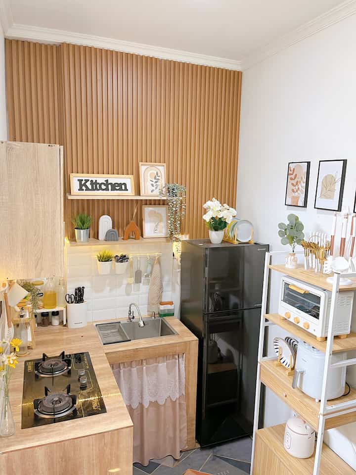 Compact kitchen in wood tone and white color, featuring sink and home appliances with a minimal, tidy layout