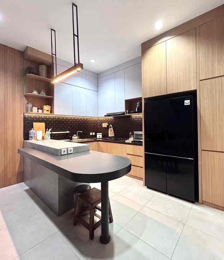 Area dapur kami berukuran 2,5x4 dengan model peninsula untuk menambah area kerja karena space meja yang sempit. Budget utama untuk interior memang kami spend di kitchen ini karena saya sendiri suka masak dan harapannya banyak aktivitas yang bisa dilakukan bersama keluarga kelak di kitchen ini. Kami desain sendiri dengan mengambil inspirasi dari pinterest dan disesuaikan dengan ukuran serta kebutuhan kami.

Bahan utama yang digunakan pada kabinet yaitu multipleks dan HPL , khusus top table area L di kompor dan sink menggunakan batu granit blackgold agar lebih awet dan tidak mudah kotor. HPL yg dipilih masih seputar warna putih, coklat, hitam dan abu sehingga masih senada dengan interior ruang lainnya.

Backsplash menggunakan mosaic tiles warna hitam juga supaya tidak gampang kotor dengan bentuk yang unik sehingga menambah elemen dekoratif dan kesan maskulin.

Kami memilih kabinet dengan tanpa handle supaya look lebih simple dan clean. 

Bagian peninsula/mini bar menggunakan HPL juga agar lebih low budget namun kami buat melengkung dan beda ketinggian secara desain untuk membedakan fungsi (rencana awal untuk coffee station) dan sirkulasi lebih nyaman dan aman untuk anak-anak.

Untuk dinding aksen perbatasan area dapur dan ruang makan kami berikan wood panel yang tidak terlalu besar untuk peralihan material kitchen set ke dinding polos.

Semoga menginspirasiii 🫶🏻

#MyDreamKitchen #IdeDekorDapur #KitchenMaterials #Peninsulakitchen #Modernkitchen #japandi #desaindapur #Idedesain #InteriorDesign #kitchendesign #dapurminimalis #dapurmodern #islandtable #peninsulakitchen