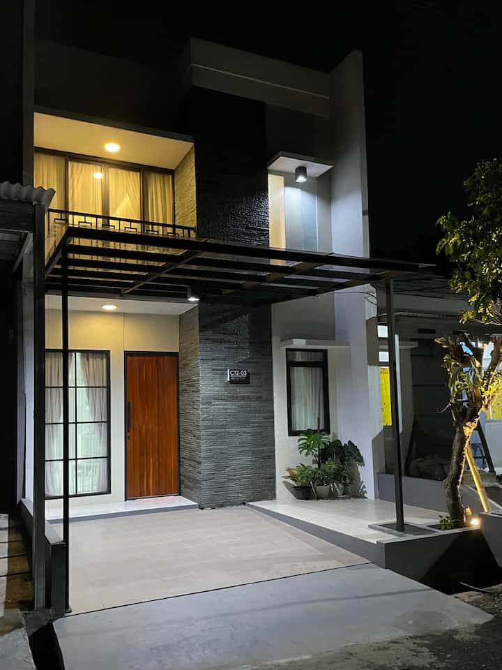 Fasad rumah kami bergaya modern minimalis dengan sentuhan wood pada pintu utama yang dilengkapi dengan lighting untuk menambah kesan dramatis. 
Teras rumah kami biarkan terbuka tanpa pagar karena mengingat lebar rumah kami minimalis hanya 5 meter maka menurut kami akan lebih nyaman jika dibiarkan terbuka untuk menambah kesan luas pada area teras. 
Kanopi yang terpasang juga sengaja tidak full menutupi seluruh teras karena kami mempertahankan pohon kamboja dan menginginkan saat hujan dapat membasahi lantai teras space tanaman.



#facadestyle
#materialfasad
#inspirasifasad
#fasadrumahminimalis
#fasadideas
#rumahminimalis
#idefasadrumah
