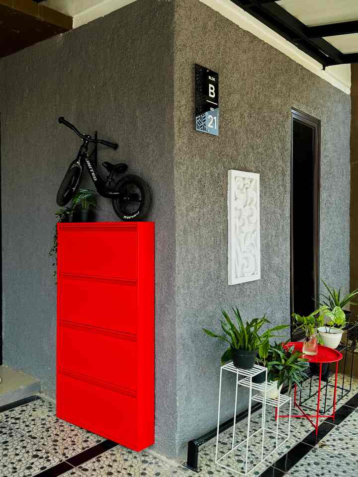 Gray-walled balcony entrance featuring a vibrant red shoe cabinet and multiple potted plants creating a natural ambiance