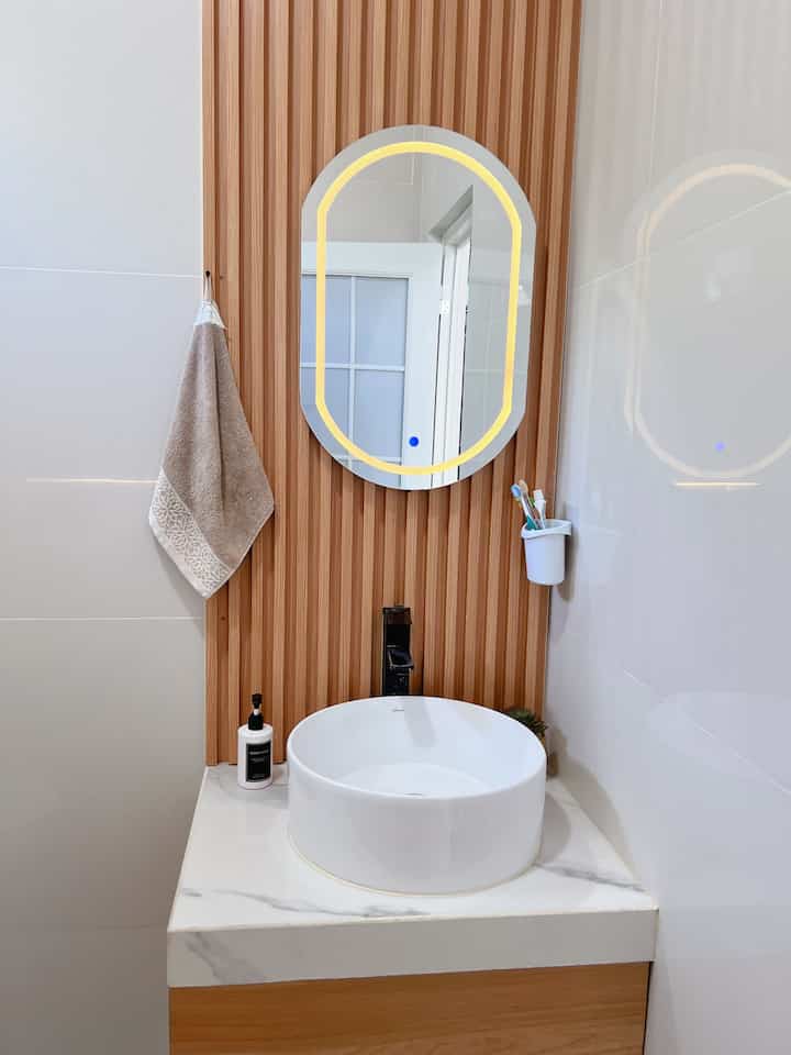 Natural wood-tone fluted wall with round wash basin in a simple and clean bathroom space