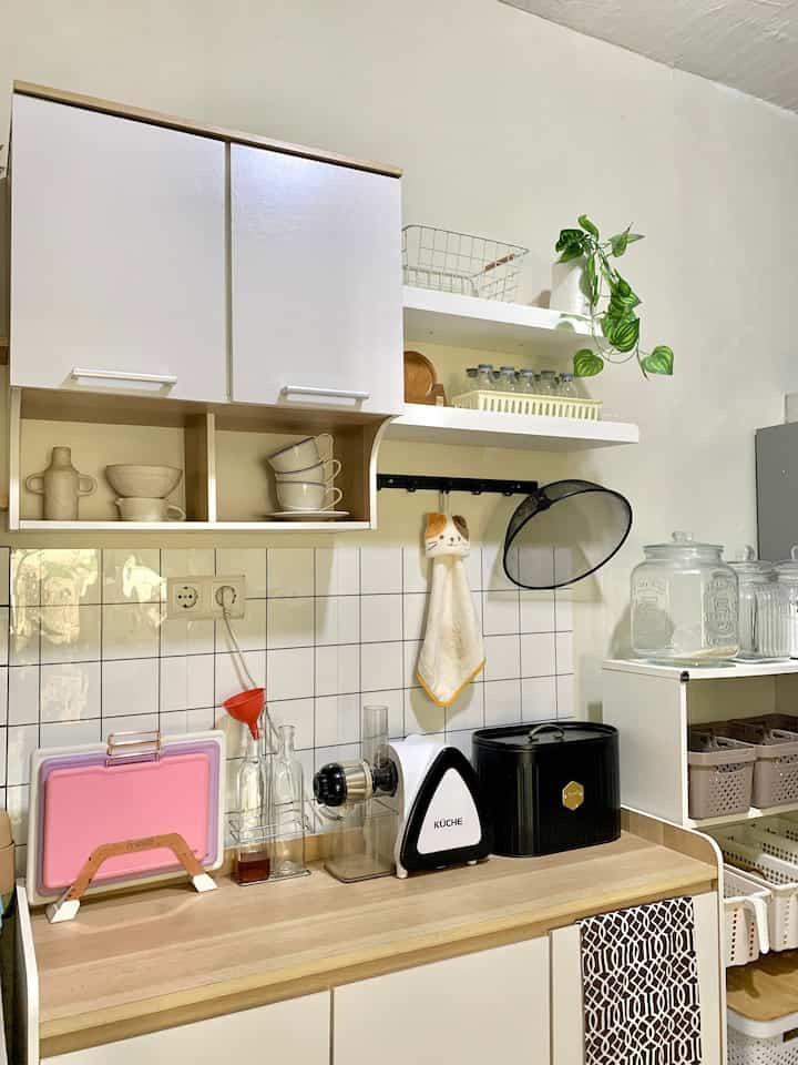 White and wood tone kitchen space featuring neatly organized storage and kitchen utensils with a practical atmosphere