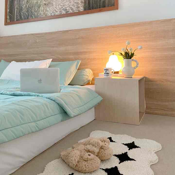 White and wood tone bedroom featuring a bed, nightstand, and soft lighting creating a cozy minimalist interior