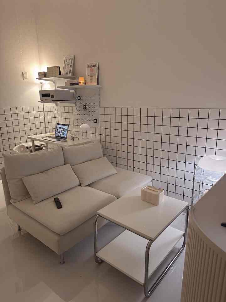 White-toned small living room featuring a white sofa and coffee table with a modern, cozy atmosphere