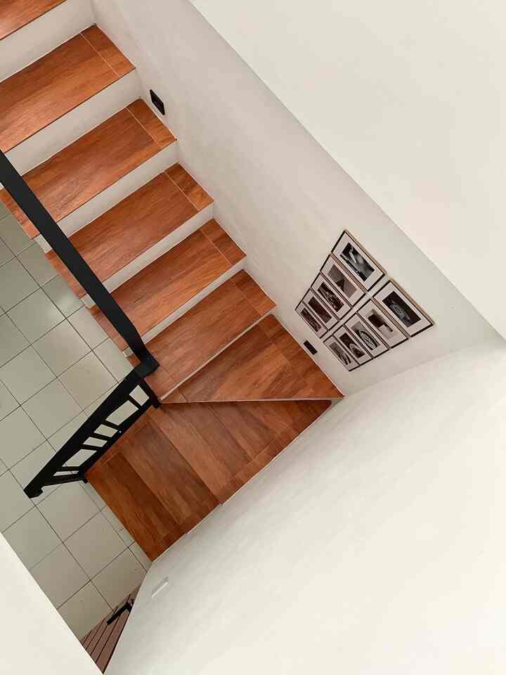 Simple stair space with white walls, wood-tone stairs, black railing, and black-&-white framed wall decor