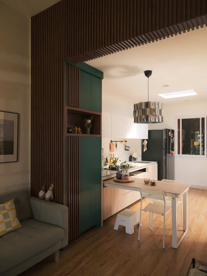 Mid-century and Japandi style living and kitchen space featuring a green cabinet with dark brown wood paneling divider